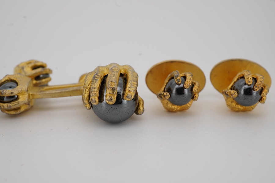 A modern gilt sterling and hematite set six piece dress stud set, modelled as a hand grasping a sphere, comprising a pair of cuff links 30mm and four studs. Condition - poor to fair